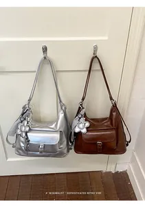Silver and brown minimalist multifunctional hobo bags hanging on white door hooks.