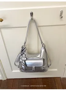 Detailed view of a silver metallic hobo bag hanging with stylish flower charm accessory.