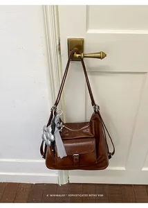 Close-up of vintage brown leather tote bag with silver flower charm detail