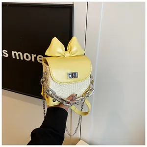 Detailed view of mini yellow bow lipstick bag with silver chain and woven texture