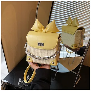 Detail view of yellow bow mini bag with woven texture and silver chain strap