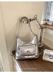 Silver multifunctional women's bag with a sleek retro vibe displayed on a desk