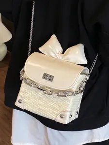 Trendy mini cream crossbody bag featuring a large bow and decorative silver chain