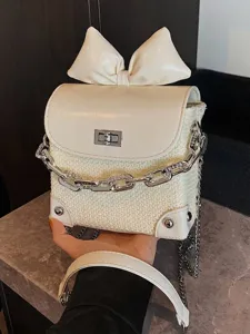 Elegant mini white woven crossbody bag featuring a large bow and silver chain strap