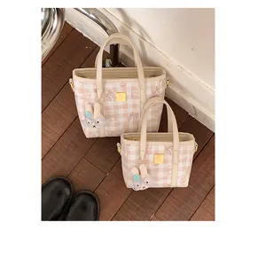 Detail of two pink gingham tote bags in different sizes with a cute rabbit charm.