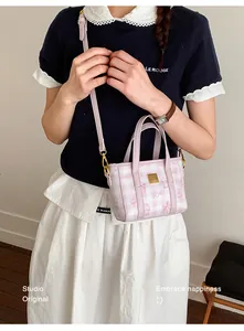 Lifestyle view of a stylish pink and white checkered crossbody bag with cat motifs