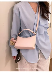 Close-up of a stylish pink crossbody bag worn with a blue shirt and teddy charm