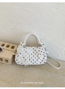 Detailed view of white polka dot handbag with elegant lace bow and pearl accessories