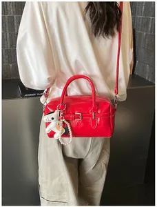 Detailed view of a vibrant red glossy leather Boston bag with a stylish horse charm.