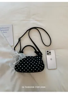Detail view of the black polka dot dumpling bag with white mesh bow and pearl strap.