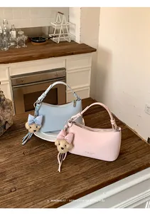 Close-up of pastel blue and pink underarm bags with cute teddy bear charms on a wooden table.