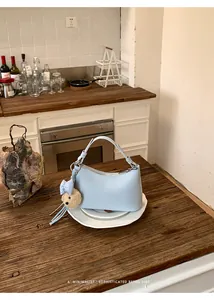 Elegant light blue hobo bag with teddy charm displayed on a rustic wooden table