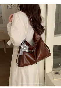 Vista posteriore di una grande borsa tote in pelle marrone indossata da un modello femminile