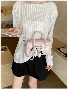 Stylish pink Boston pillow bag with horse charm carried by model in a cafe setting