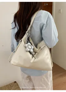 Grande borsa tote beige minimalista portata a spalla da modella con ciondolo a fiore