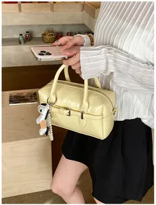 Detailed view of a stylish yellow Boston bag featuring a cute puppy charm and pearl strap