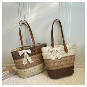 Détail de deux sacs fourre-tout en paille tissés main avec nœuds en dentelle et anses.