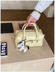 Detail view of a cream-colored Boston bag with a white horse charm and leather texture.