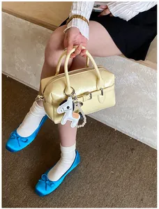 Detail view of the pale yellow Boston pillow bag with horse charm held by model