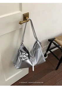 Borsa tote oversize argento metallizzato appesa a una maniglia retrò in stile minimal