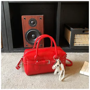 Shiny red patent leather Boston bag with belt strap detail and horse charm decoration