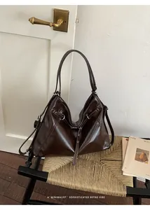 Borsa tote retrò marrone scuro dal design minimalista su una sedia di vimini intrecciata