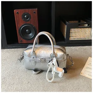 Detailed view of a metallic silver Boston bag featuring a crinkled texture and dog charm