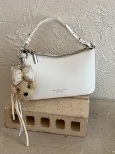 Minimalist white leather underarm shoulder bag featuring a cute plush bear keychain accessory