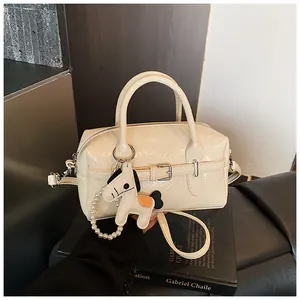 Detailed view of off-white Boston bag with decorative horse charm and pearl strap