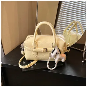 Detail shot of chic cream Boston bag with crinkled texture and pearl horse charm.