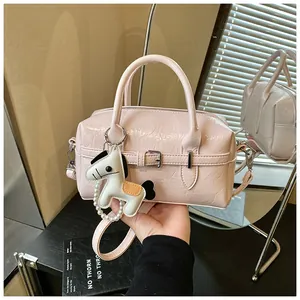 Close-up of pink crinkled leather Boston bag featuring a decorative white horse charm