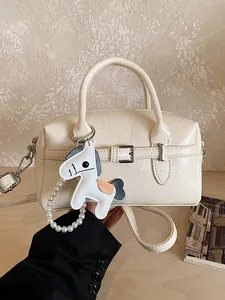 Chic cream Boston pillow bag for women featuring a stylish horse charm accessory