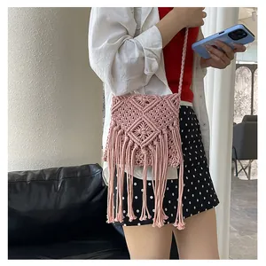Macro view of handmade pink woven crossbody bag featuring stylish long fringe tassels