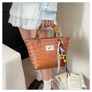 Bolso cesta marrón tejido a mano con asas de bambú y colgantes decorativos de colores