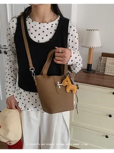 Elegante vrouw draagt een bruine vintage lederen emmertas met een kleine paardenhanger