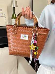 Bolso tote tejido marrón grande con asas de bambú y colgante de estrella para vacaciones.
