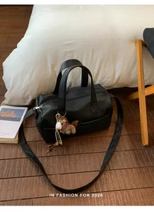 Detail of black pebbled leather pillow bag with stylish wide shoulder strap and charm.