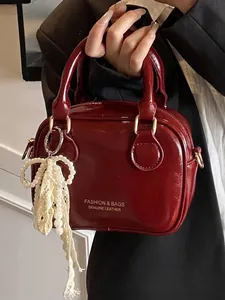 Elegant burgundy glossy patent leather handbag for women featuring a pearl bow charm detail
