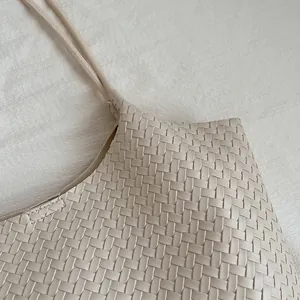 Close-up detail showing the intricate woven texture of a minimalist beige faux leather tote bag.