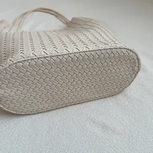 Close-up bottom view of a vintage beige woven tote bag showing intricate handmade texture.