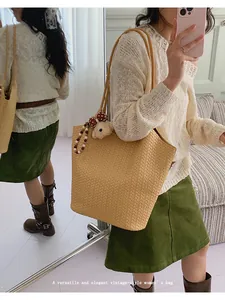 Close-up detail of a vintage-style woven tote bag worn on the shoulder by a model