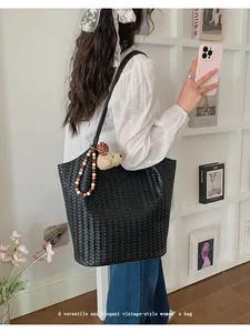 Elegant black woven tote bag with vintage style charm and cute plush bear pendant