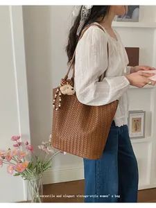 Lifestyle shot of a woman wearing a brown woven vintage-style large capacity tote bag
