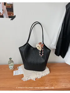 Macro view of a black woven tote bag featuring a cute bear charm for daily work.