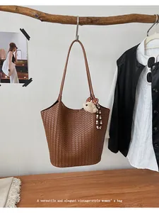 Close-up showing the elegant woven texture of a vintage brown tote bag with a bear charm