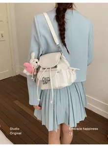 Stylish creamy white backpack with silver bow and rabbit charm worn by a model