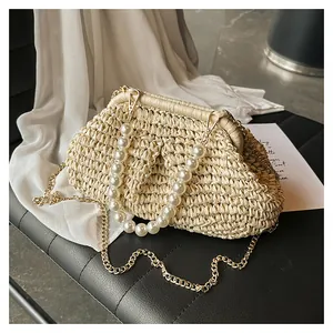 Detail view of a vintage pleated straw clutch bag with pearl handle and gold chain.