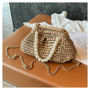Close-up of vintage straw woven clutch bag with pearl handle and gold chain