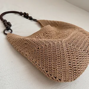 Detailed view of handmade crochet straw bag with dark wooden bead handle.