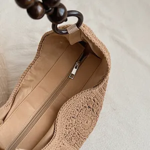 Detailed close-up of woven straw beach bag interior with metal zipper and wooden beads